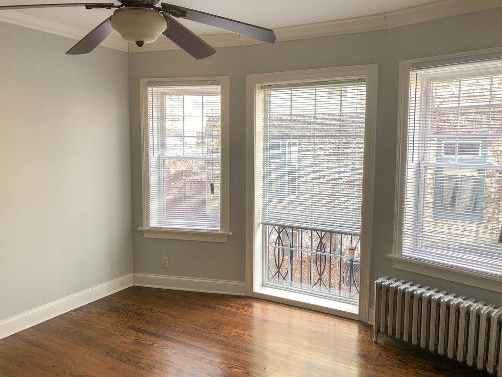 a living room with a ceiling fan and three windows