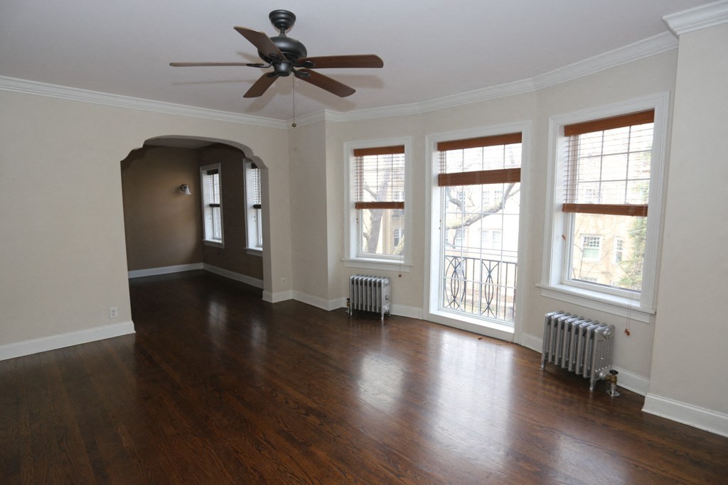 an empty living room with wood floors and a ceiling fan