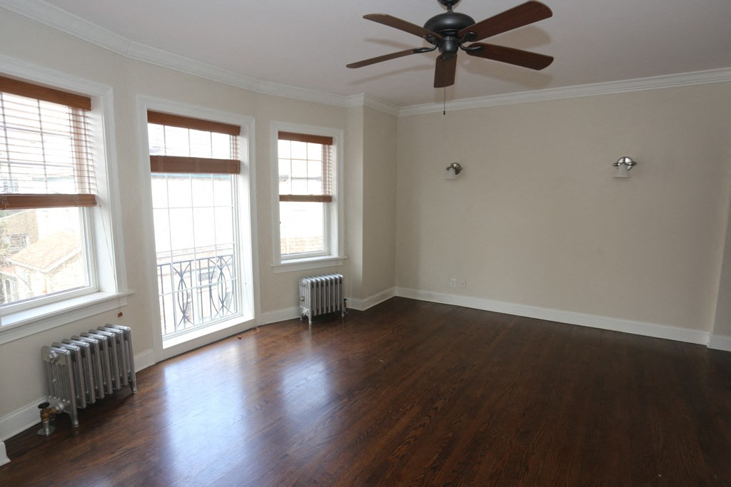 an empty living room with wood floors and a ceiling fan