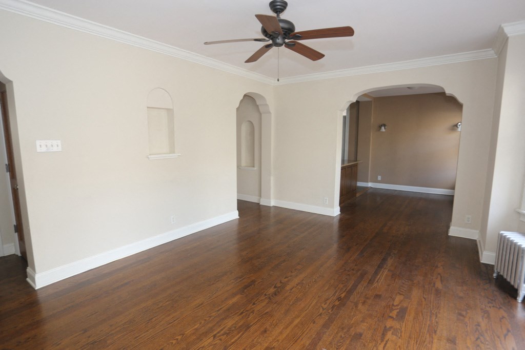 an empty living room with wood floors and a ceiling fan