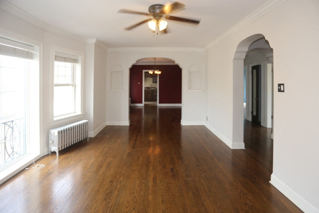 an empty living room with wood floors and a ceiling fan