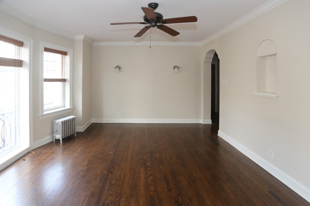 an empty living room with wood floors and a ceiling fan