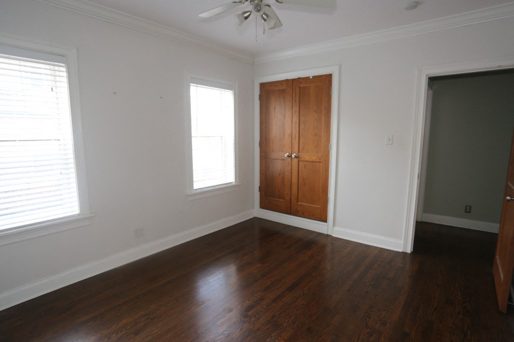 an empty living room with wooden floors and a wooden cabinet and a door