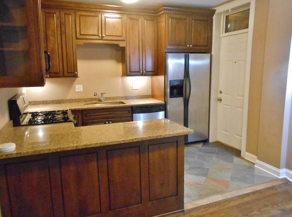 an empty kitchen with wooden cabinets and a stainless steel refrigerator