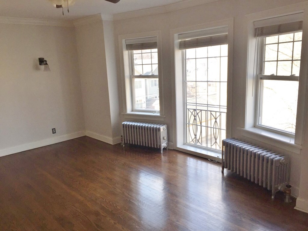 an empty living room with wood floors and three windows