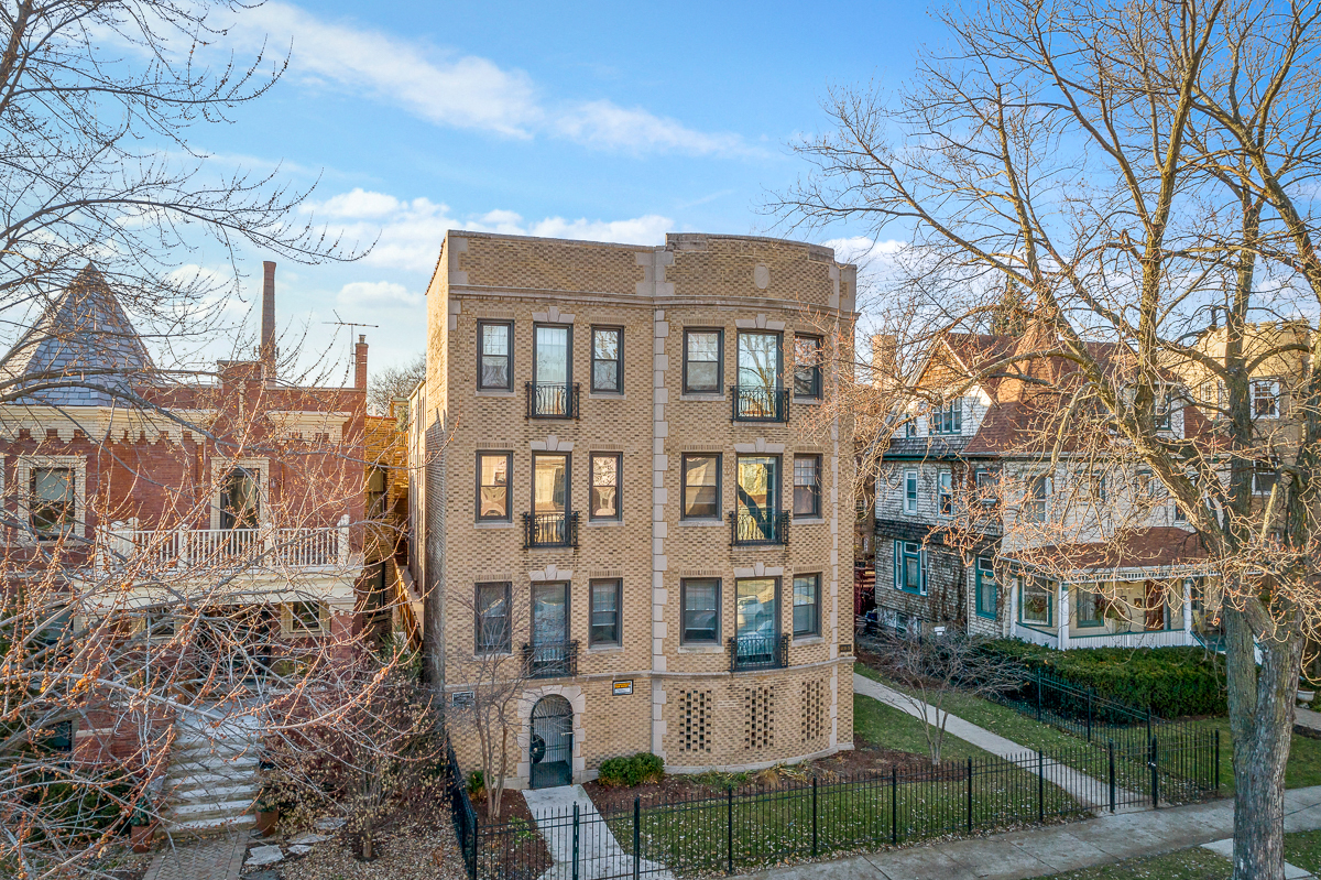 the facade of a brick apartment building with trees and a sidewalk
