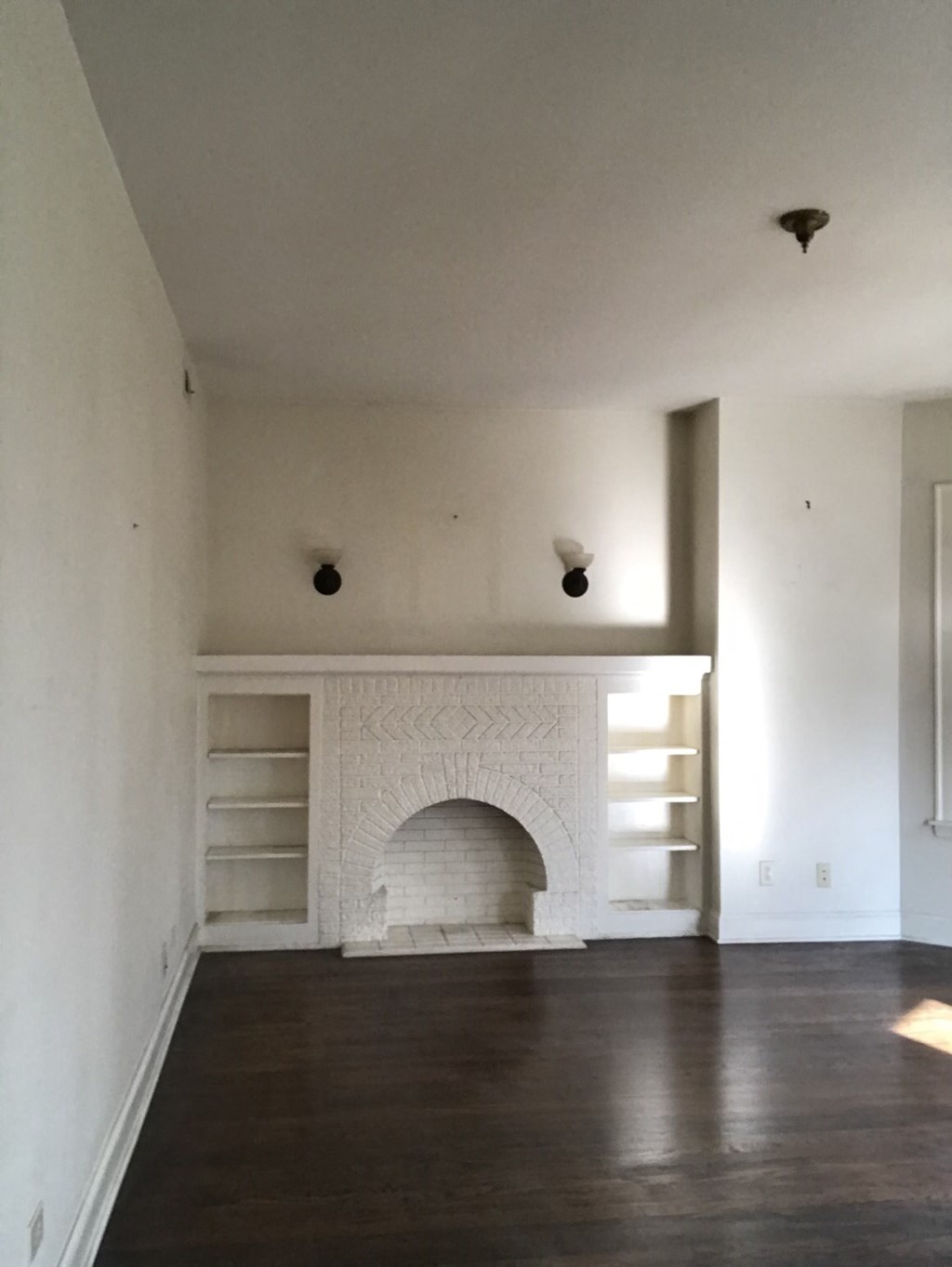 an empty living room with a fireplace and white walls