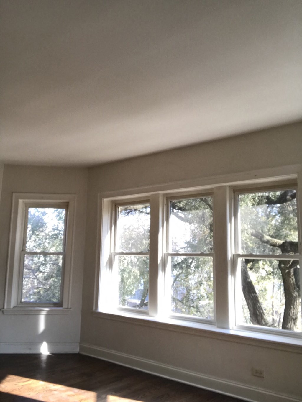 a view of three windows in a living room with a wooden floor