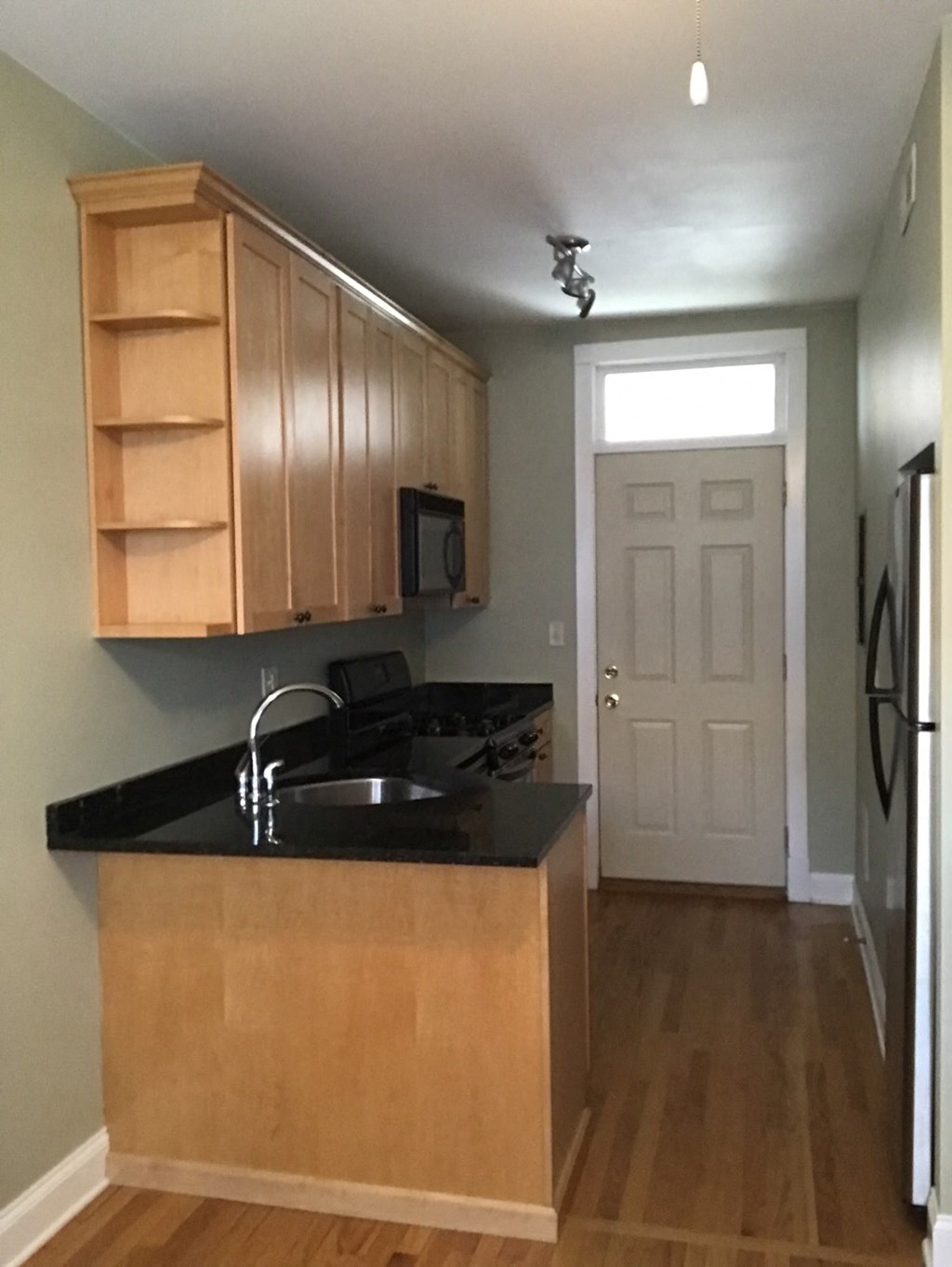 an empty kitchen with wooden cabinets and a black counter top