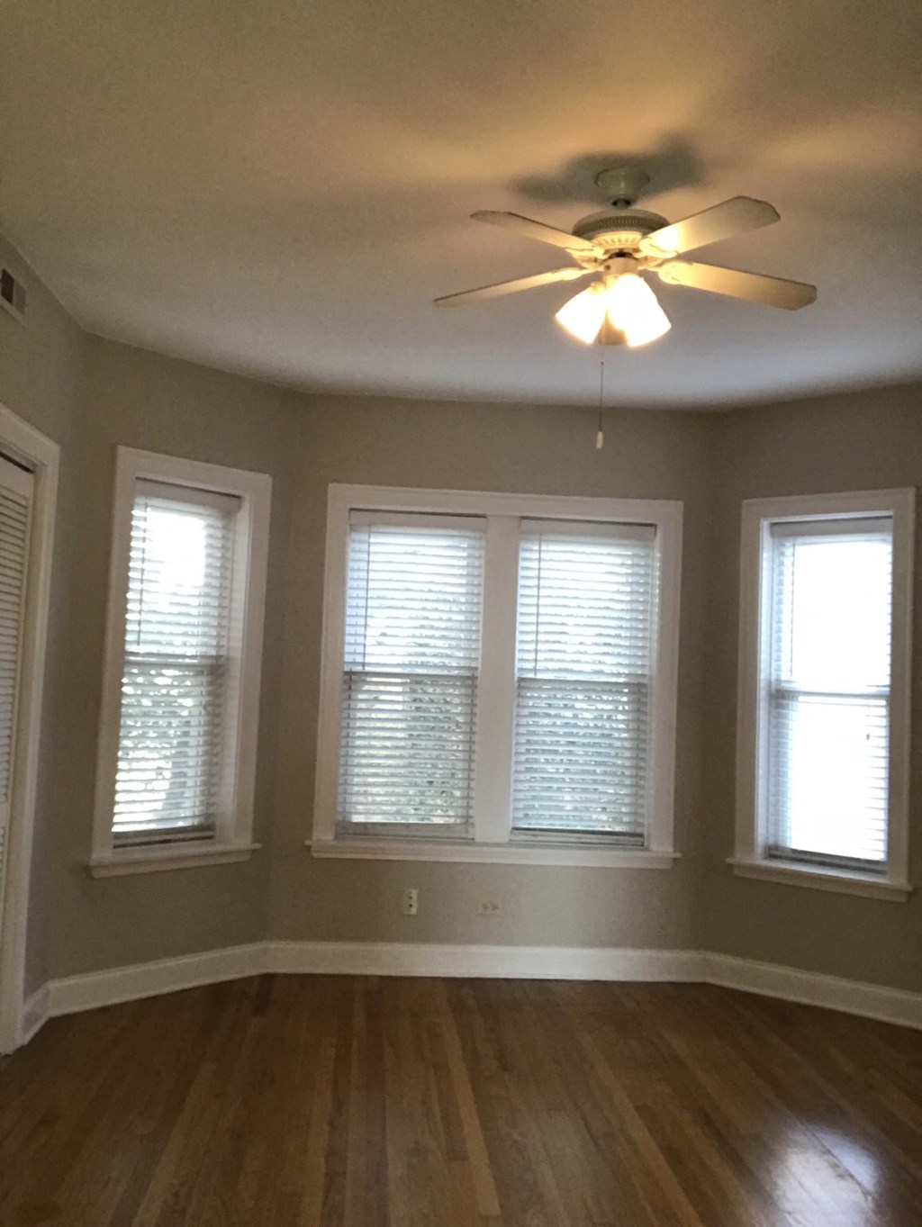 three windows in a living room with a ceiling fan