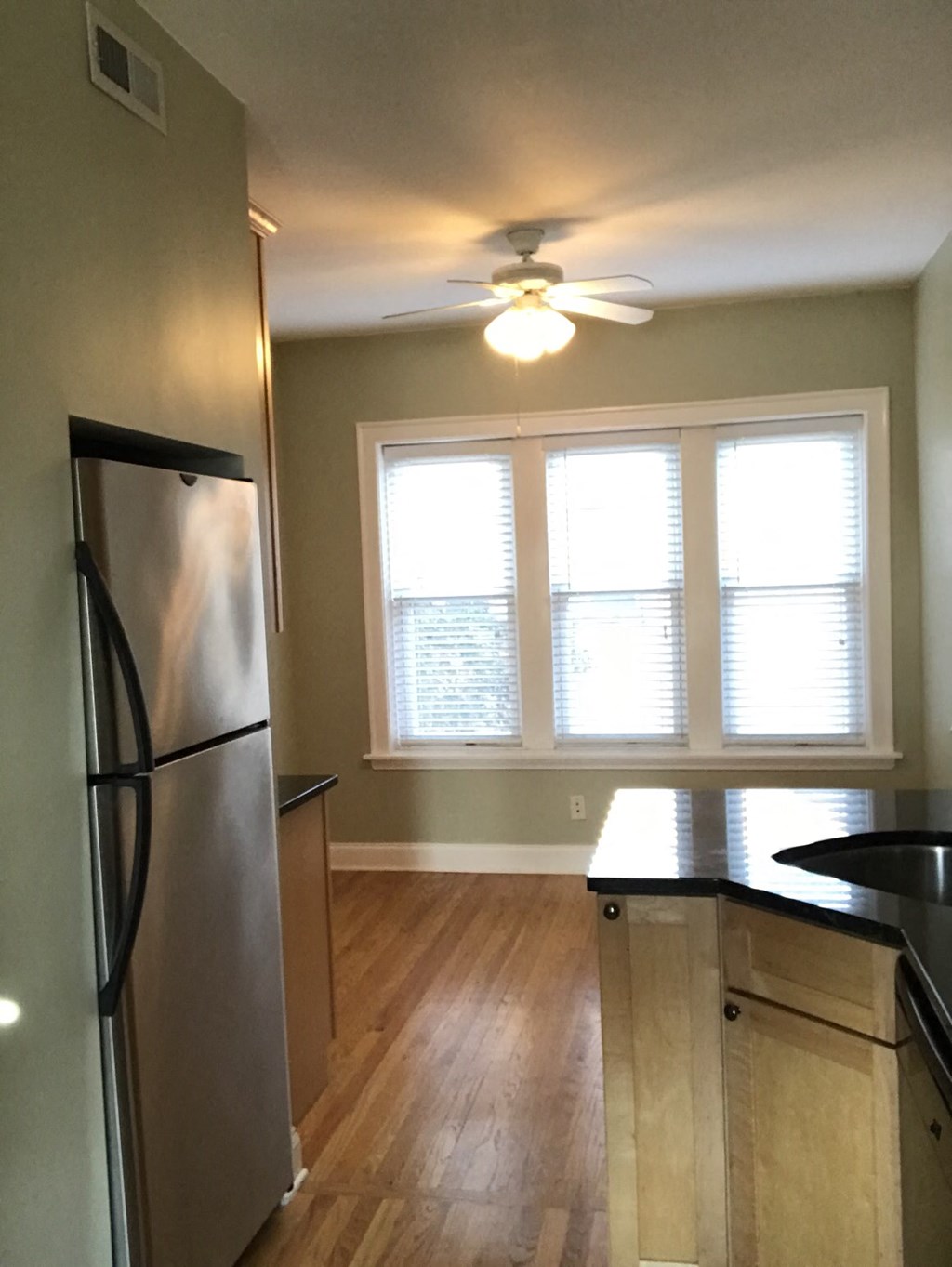 an empty kitchen with a ceiling fan and a window