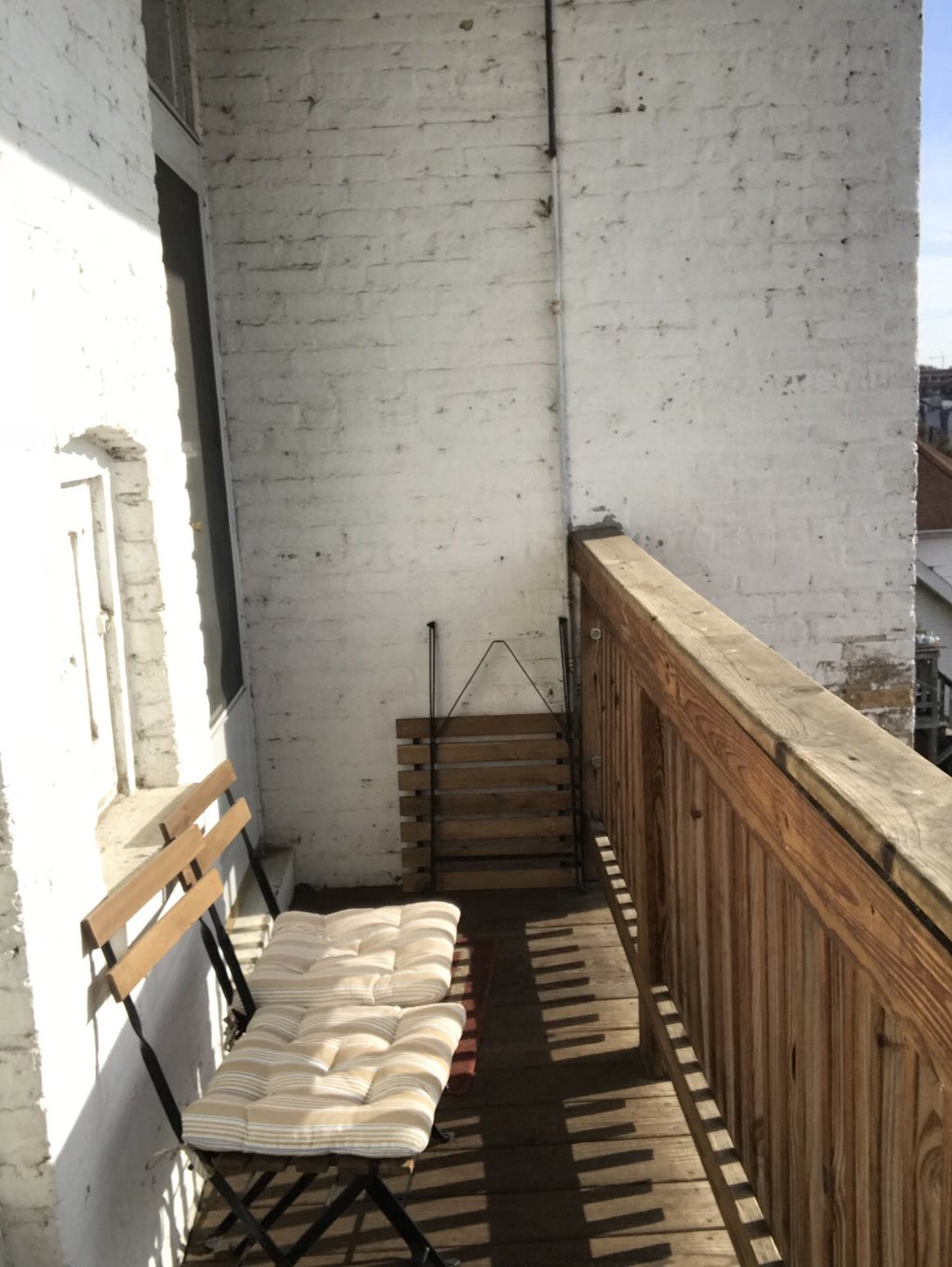a balcony with two chairs and a wooden railing