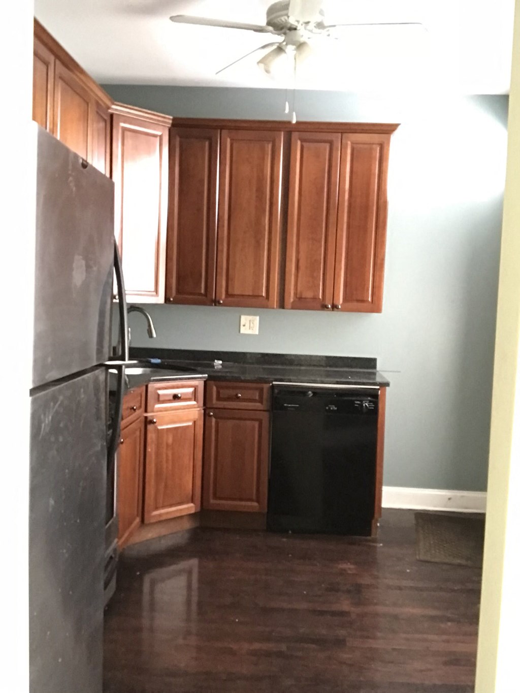 a kitchen with wooden cabinets and a black refrigerator