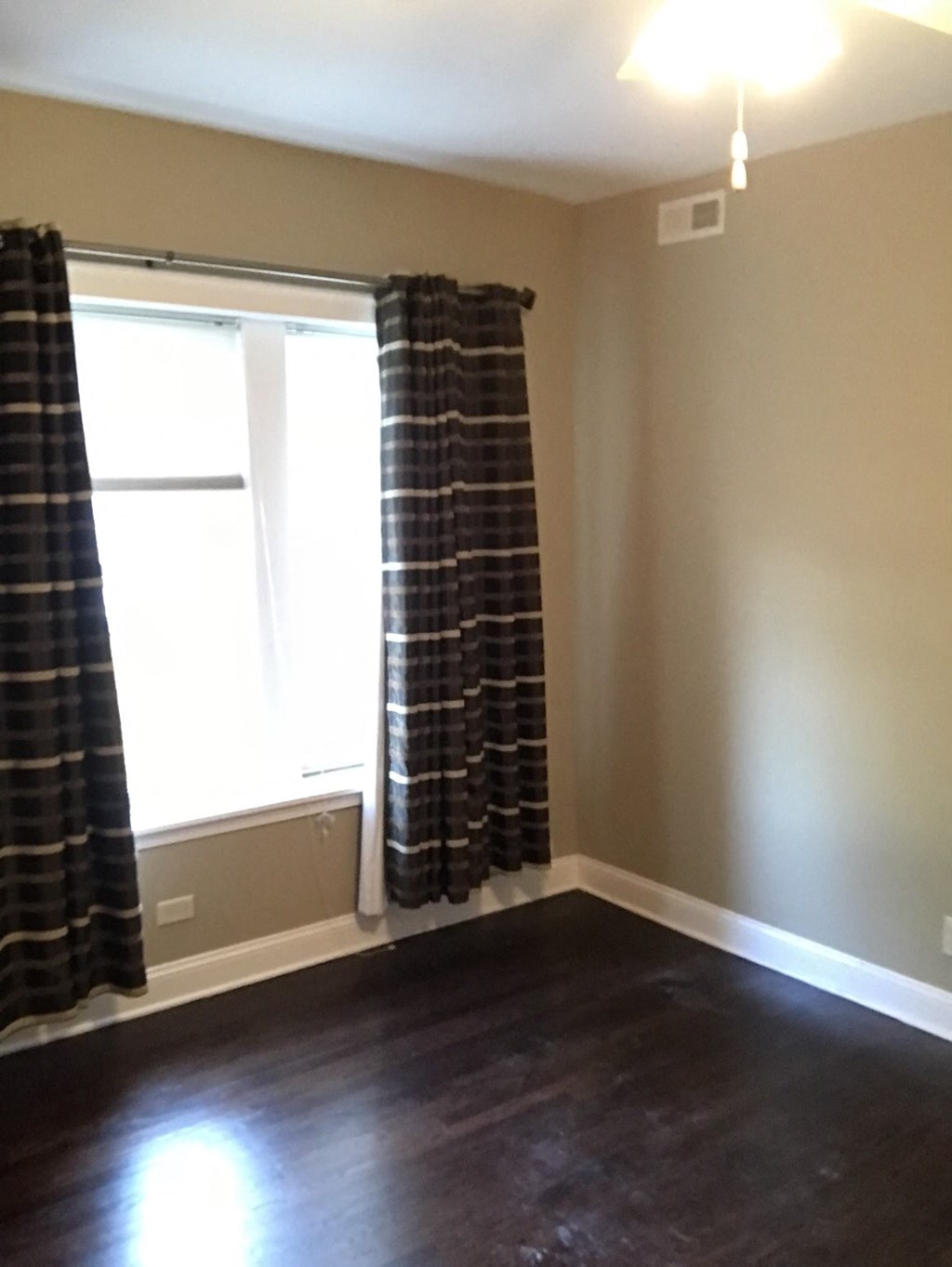 an empty living room with a window and curtains