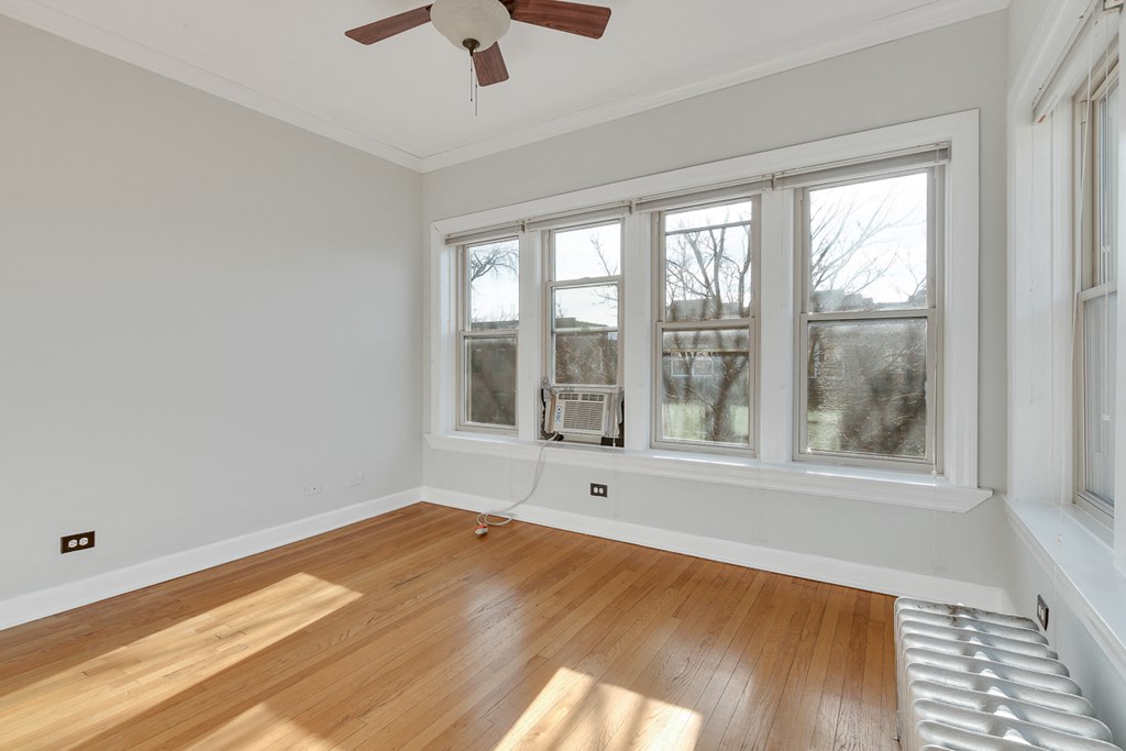 an empty living room with wood floors and a ceiling fan