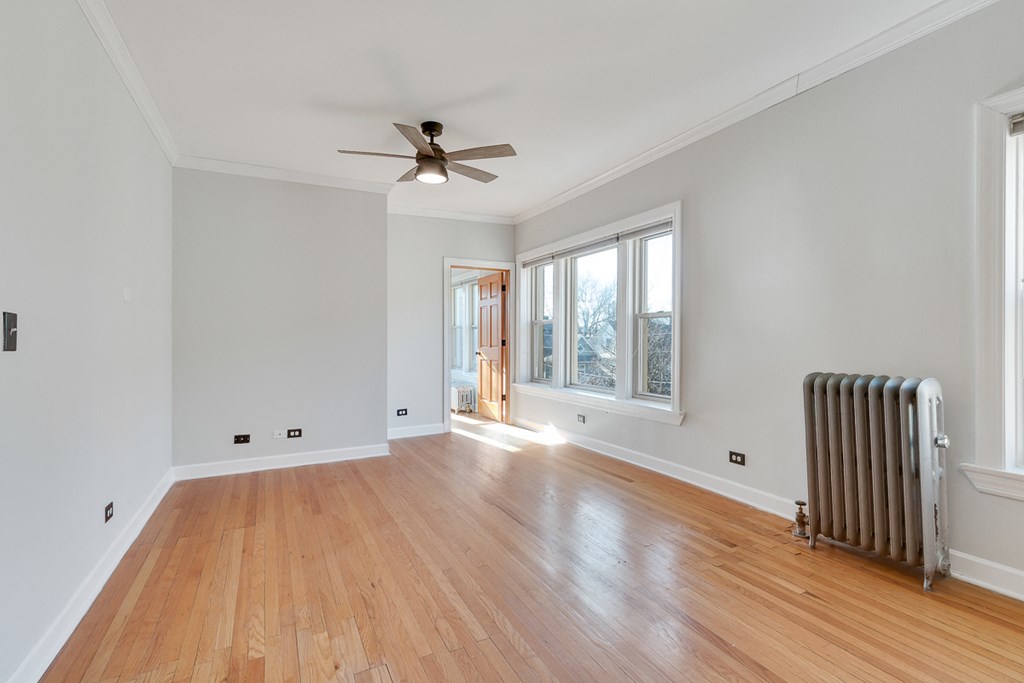 an empty living room with a radiator and a ceiling fan