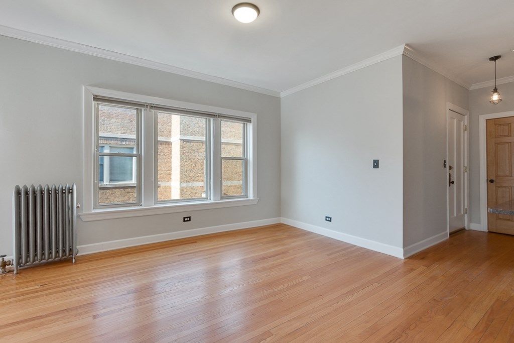 an empty living room with a radiator and a window