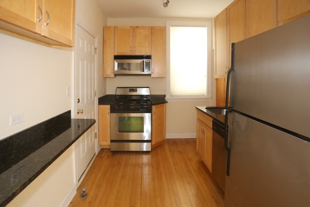 a kitchen with wooden floors and stainless steel appliances