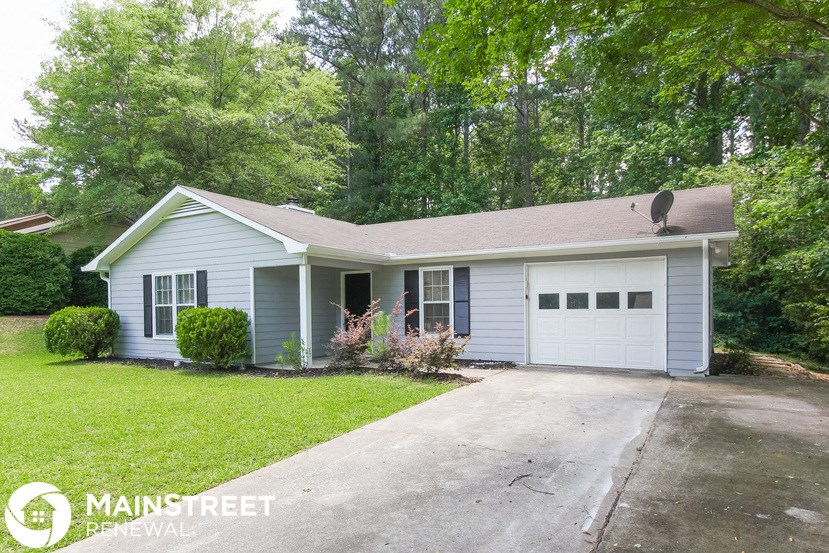 a white and blue house with a driveway and trees