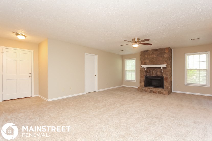 an empty living room with a fireplace and a ceiling fan