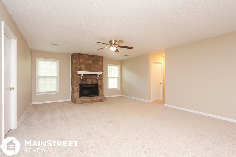 an empty living room with a fireplace and a ceiling fan