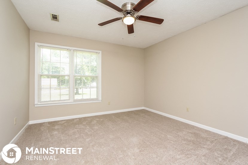 the master bedroom has a carpeted floor and a ceiling fan