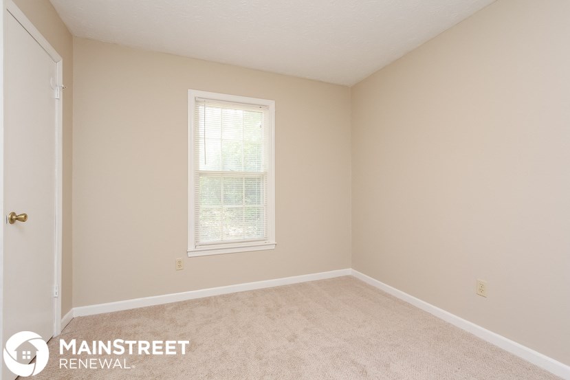 a bedroom with a carpeted floor and a window
