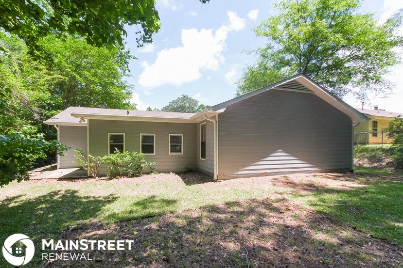 a small brown house with a lawn and trees
