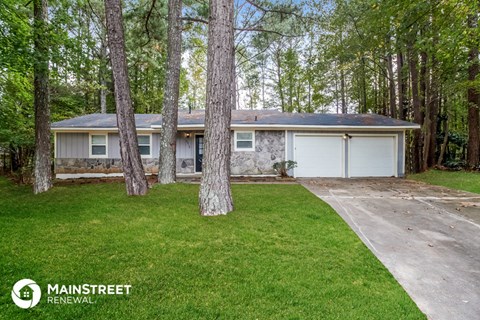 a home in the woods with a driveway and a garage door