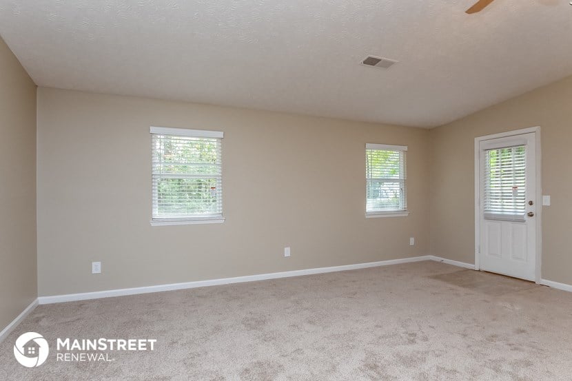 the spacious living room with carpeting and a white door