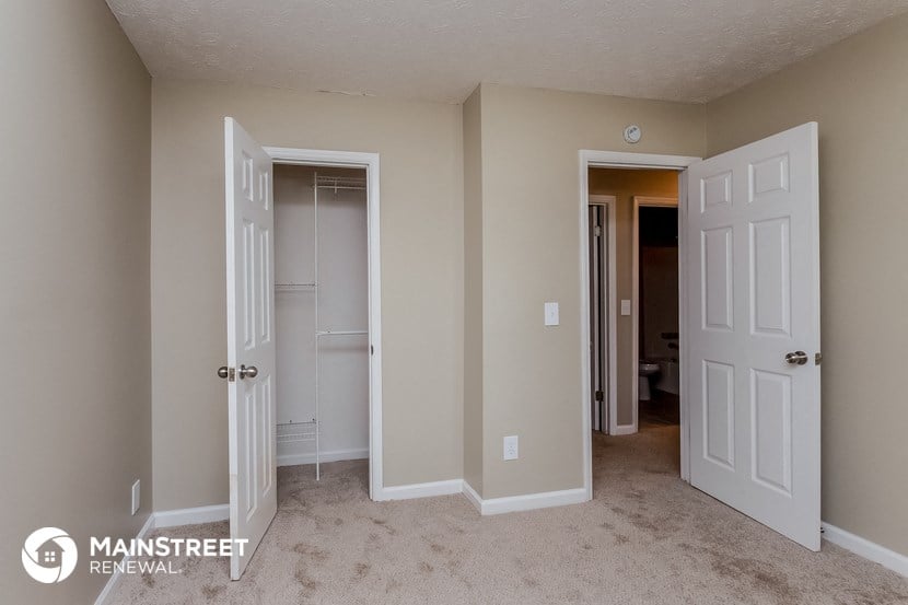 a bedroom with two closets and two doors and a carpeted floor
