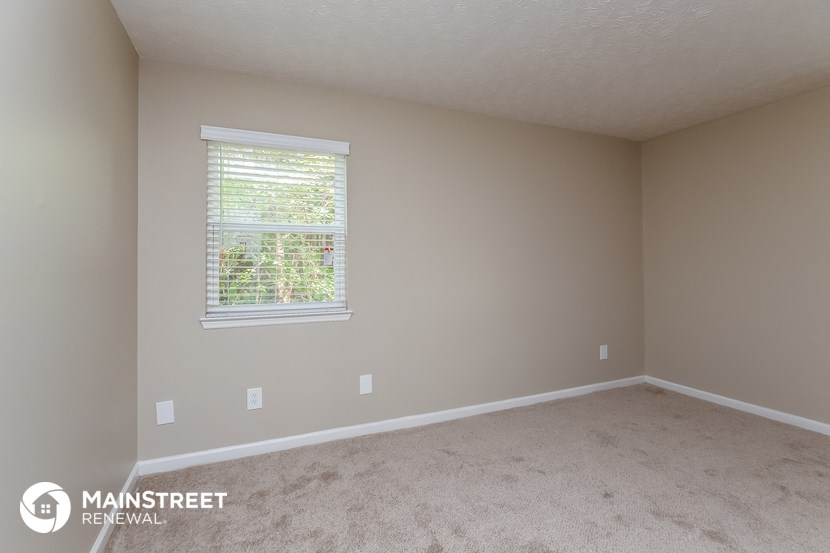 a bedroom with a carpeted floor and a window