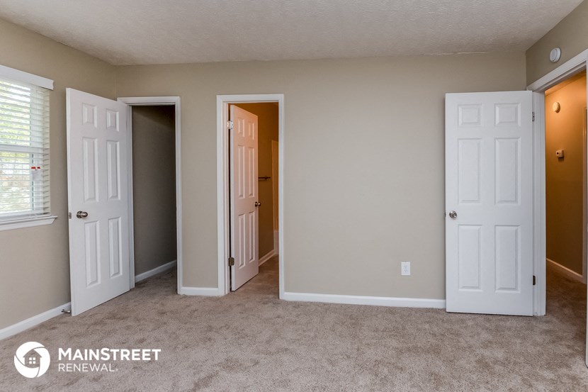 a bedroom with three doors and a carpeted floor