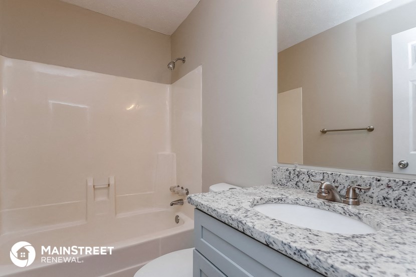 the master bathroom has a tub and a sink and a mirror