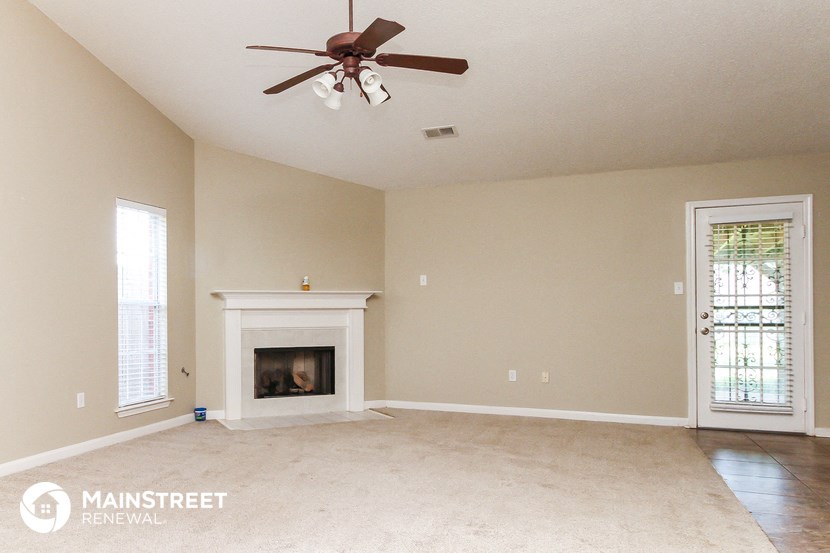 a living room with a fireplace and a ceiling fan