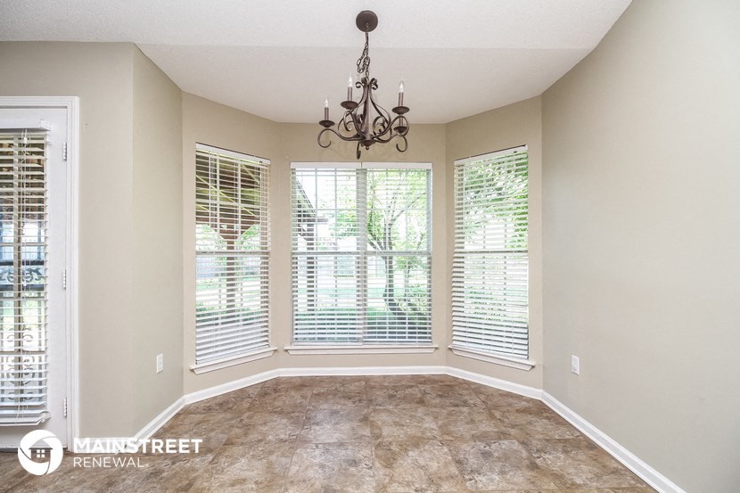 an empty living room with large windows and a chandelier