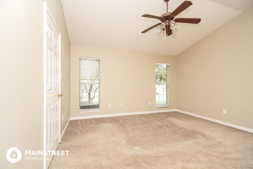a living room with carpet and a ceiling fan