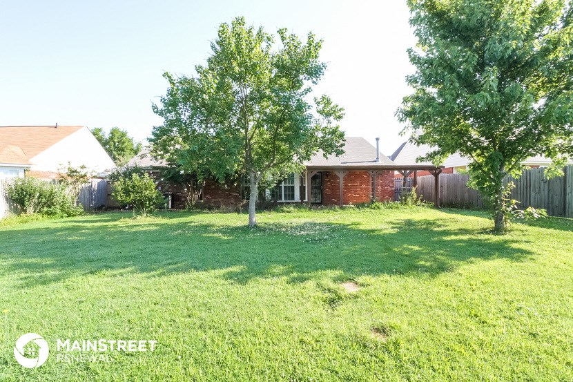 a yard with two trees in front of a house