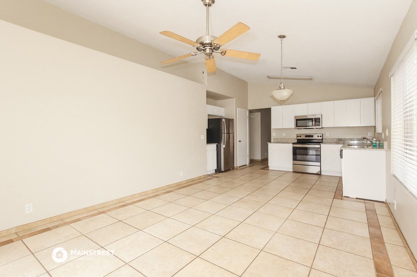 an empty kitchen with a ceiling fan and tiled flooring