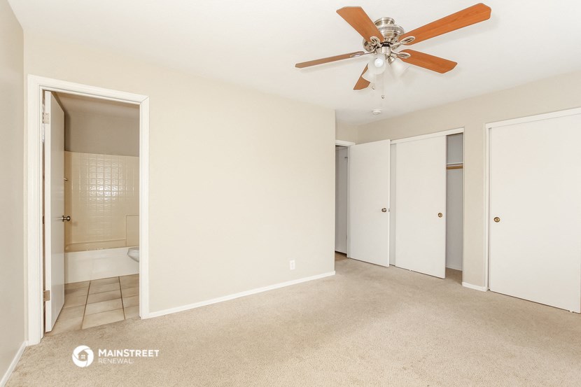 an empty living room with a ceiling fan and a bathroom