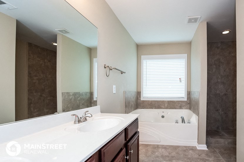 a bathroom with a large mirror and a tub and a sink