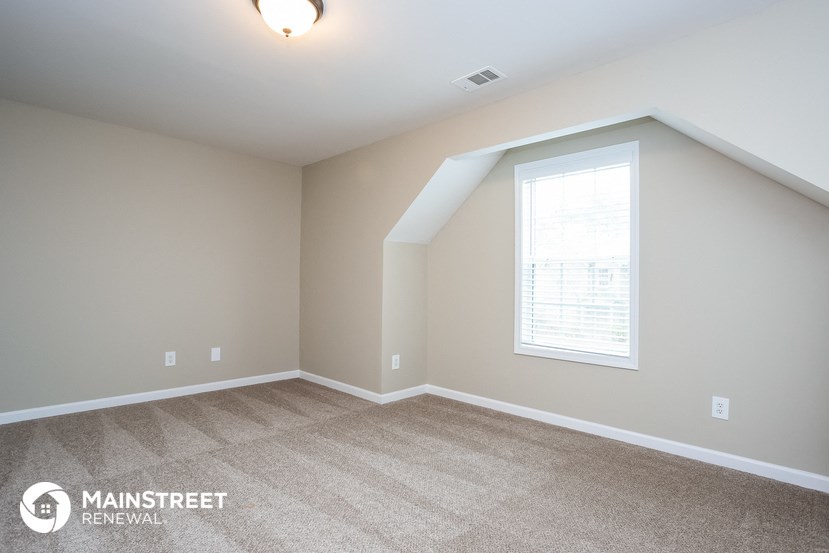 the upstairs bedroom with carpeted flooring and a window