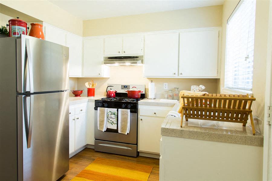 A kitchen with a stainless steel refrigerator, a stove with a pot on it, and a dishwasher.