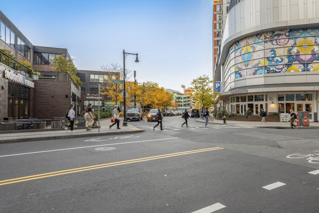 A street scene with people walking and a building with a colorful mural on the side.