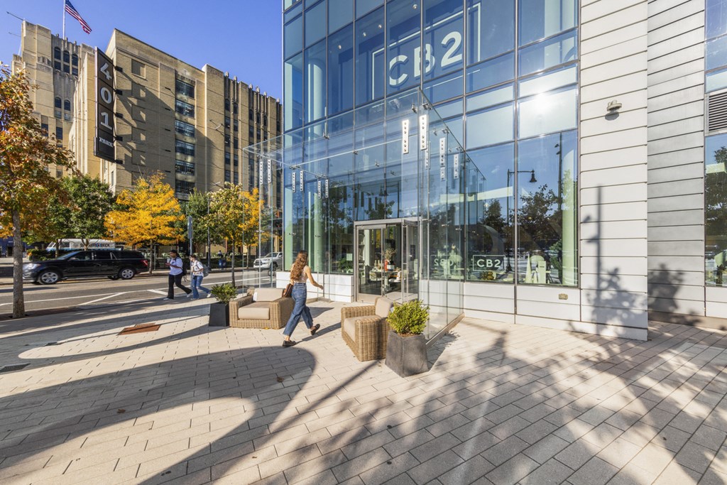 A woman walks past a building with the letters CB2 on it.