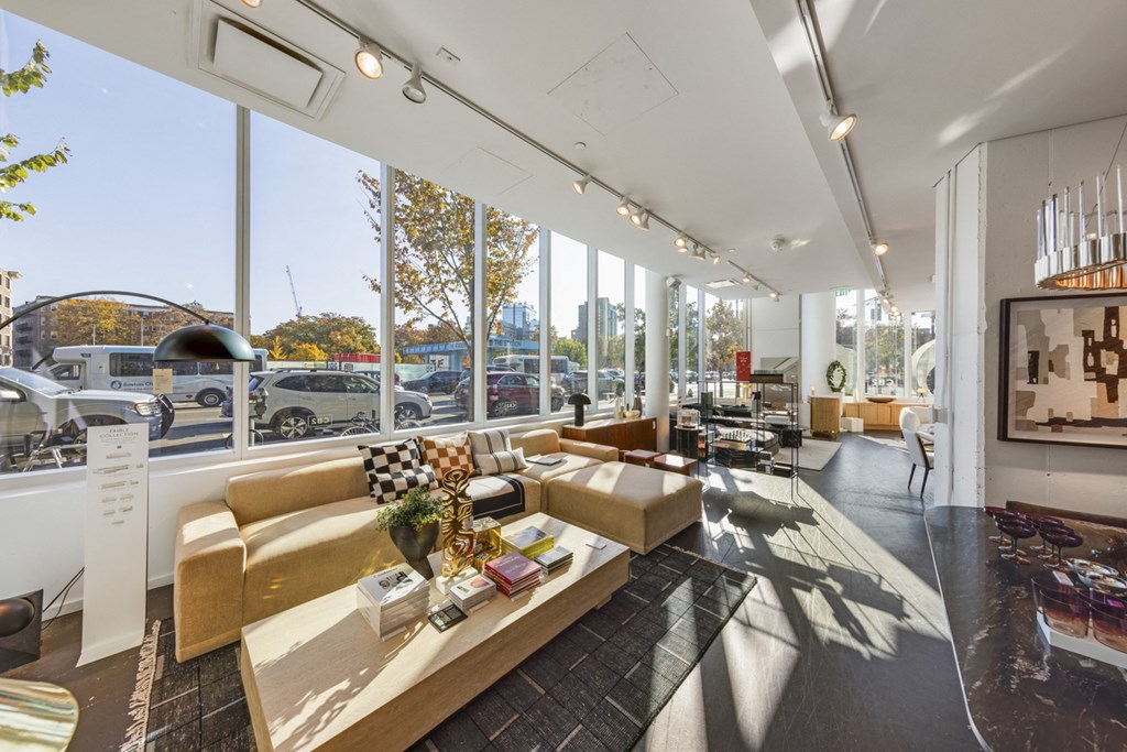 A modern living room with a large window overlooking a parking lot.