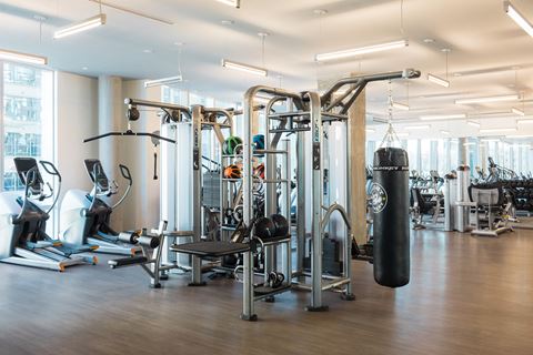 a fitness room with weights and cardio machines and a punching bag