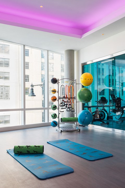 a gym with yoga mats and exercise equipment in a building with large windows