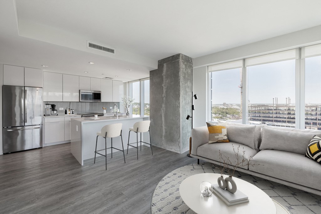 A modern kitchen with a bar stool and a grey couch.