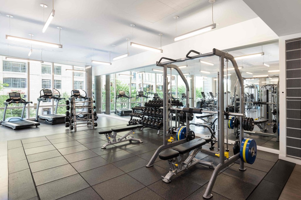 a gym with weights and cardio equipment in a building with windows